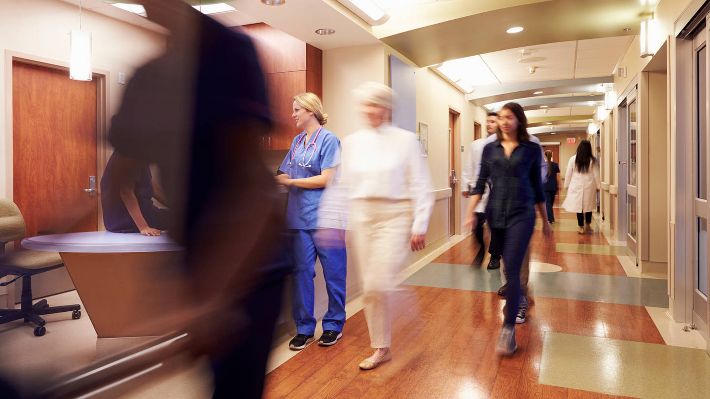 Busy hospital with blurred figures moving through a reception area