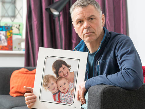 Martin Portman holds a family photo which depicts Mags Portman and their two young children