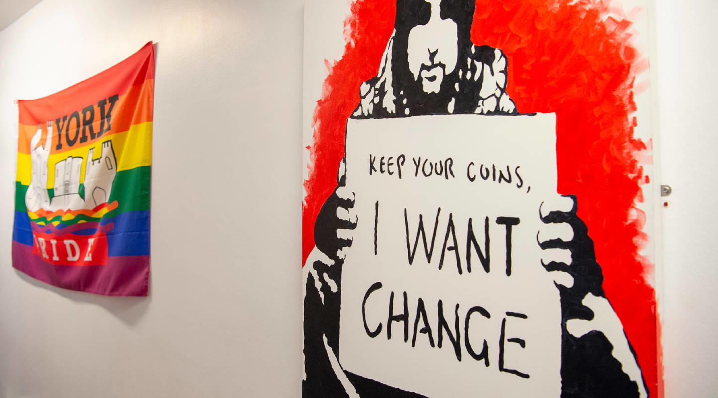 Street art depicting a homeless person holding up a sign that says Keep your coins, I want change