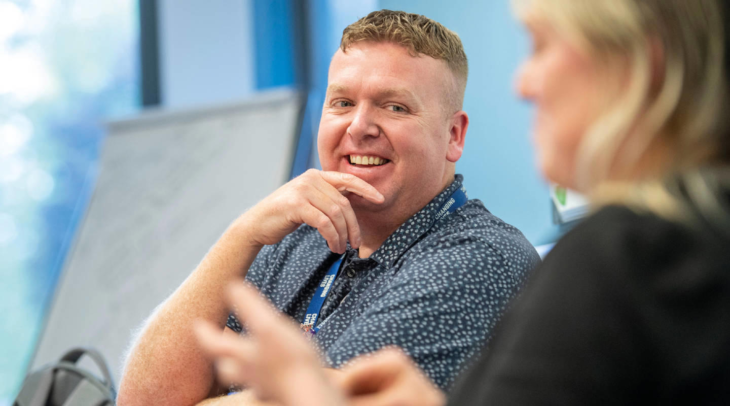 Psychotherapist Andy Ryan smiles while Helen Chidlow speaks in profile