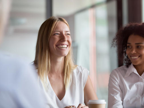 Two women in a group setting, one smiling and one laughing