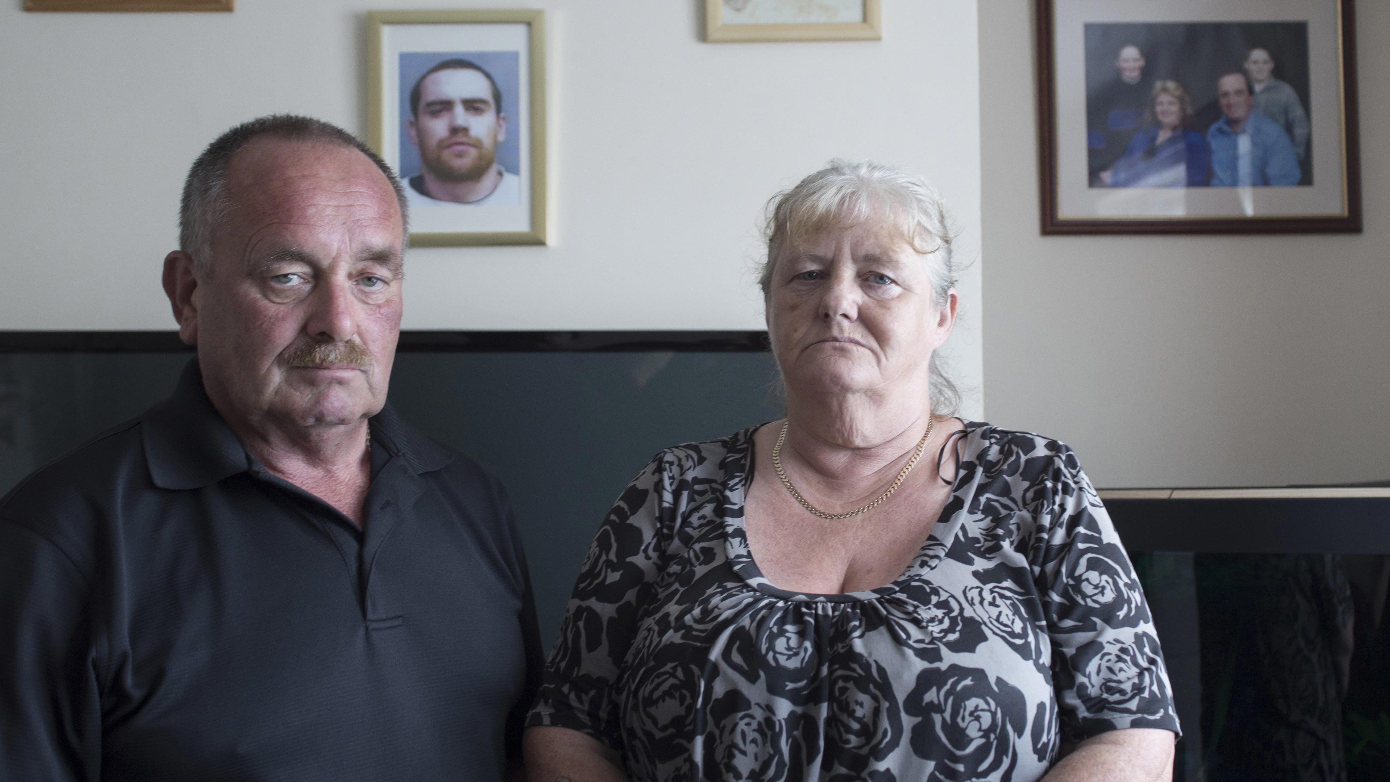 Portrait of Gerald Knight and Julie Nancarrow sat on a sofa in a living room looking to camera