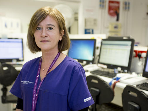A member of A&E in scrubs in a hospital setting looking to camera