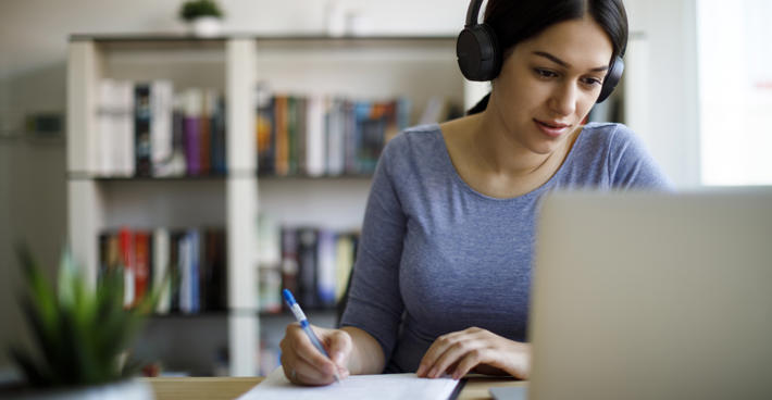 Woman taking notes at laptop