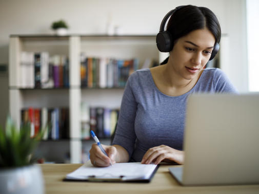 Woman taking notes at laptop