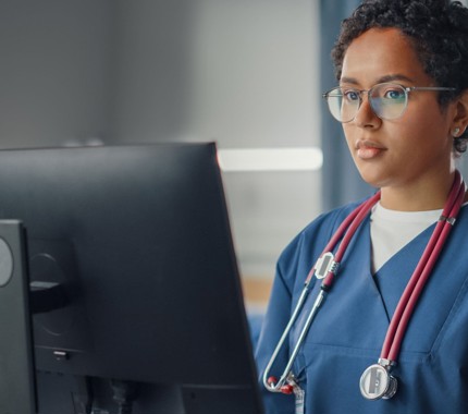 Junior doctor standing at computer in scrubs flip