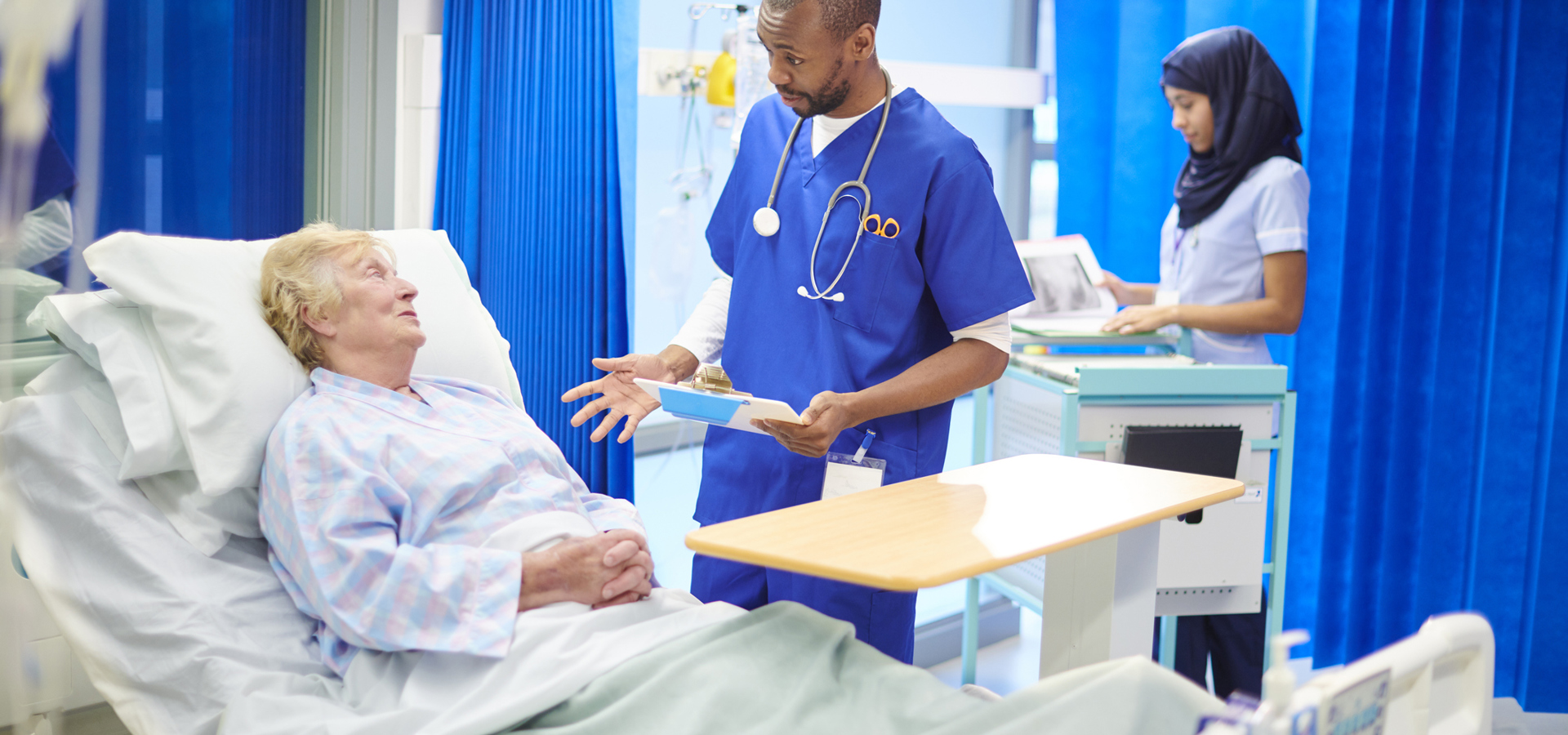 Doctor in hospital scrubs talks to elderly patient 906829760