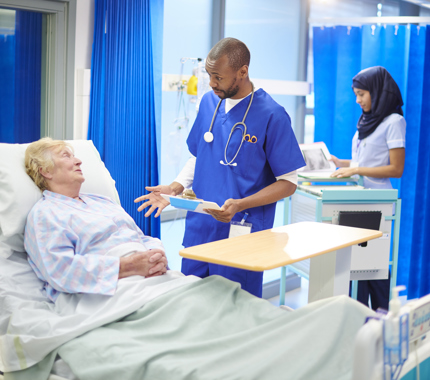 Doctor in hospital scrubs talks to elderly patient 906829760