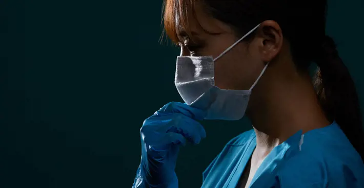 Woman In Scrubs, Mask And Gloves against dark background