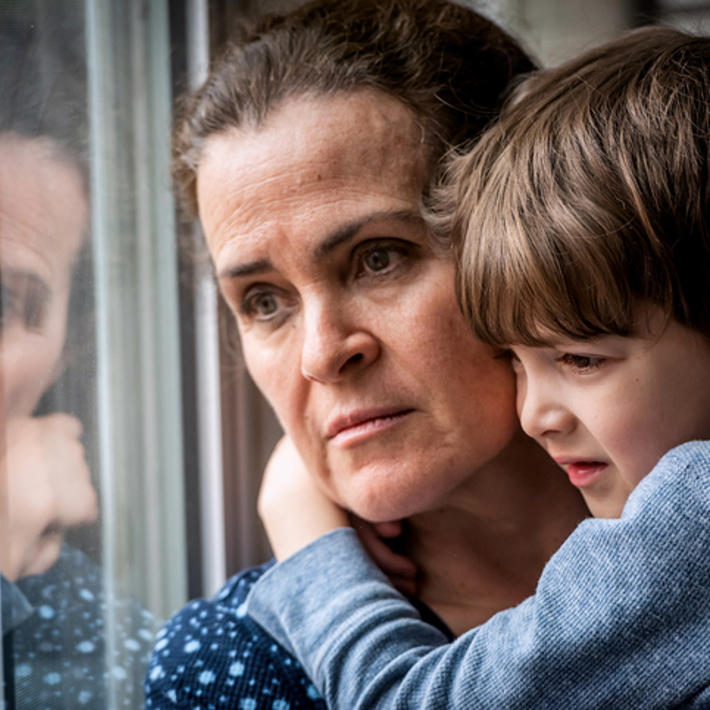 Worried Woman Holding Child And Looking Out Of Window