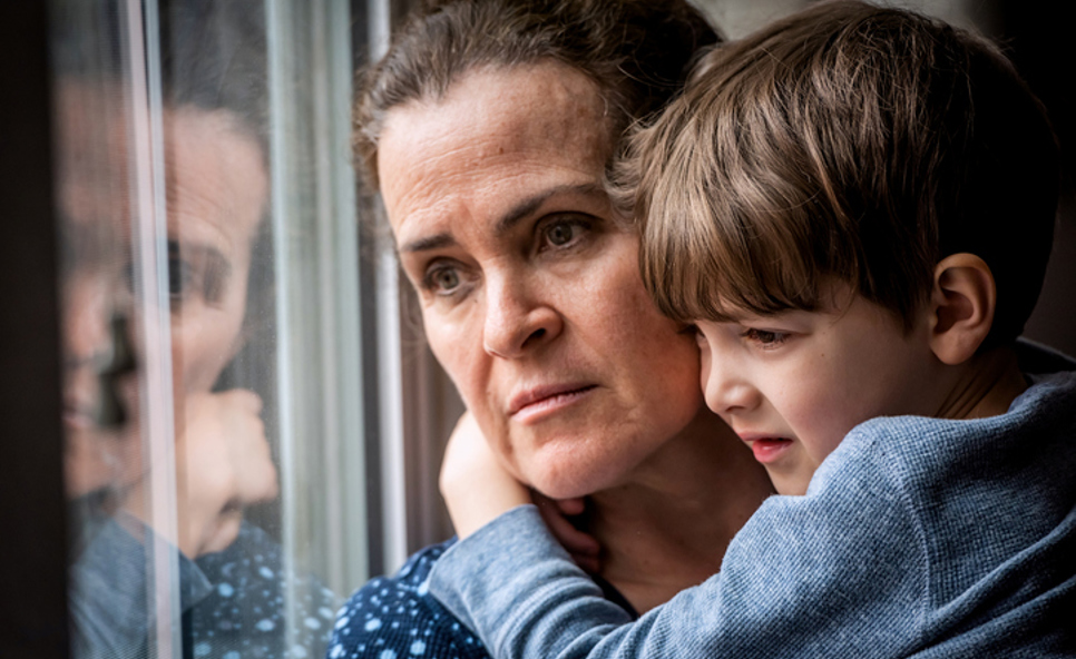 Worried Woman Holding Child And Looking Out Of Window