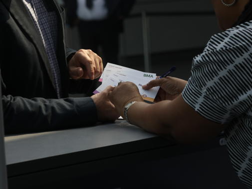Woman hands man BMA branded cards at the ARM reception desk in Liverpool