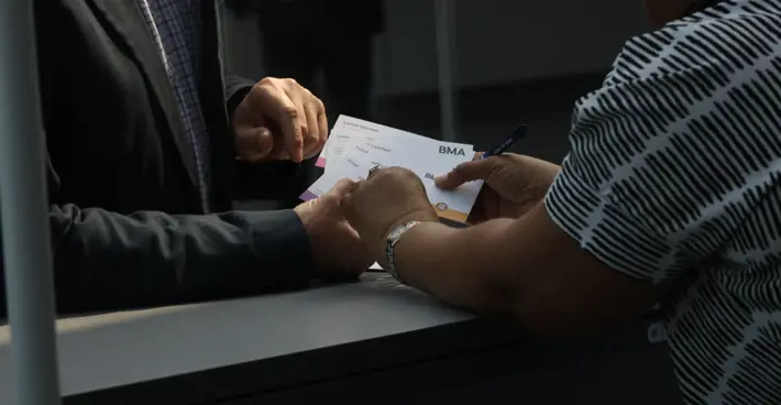 Woman hands man BMA branded cards at the ARM reception desk in Liverpool